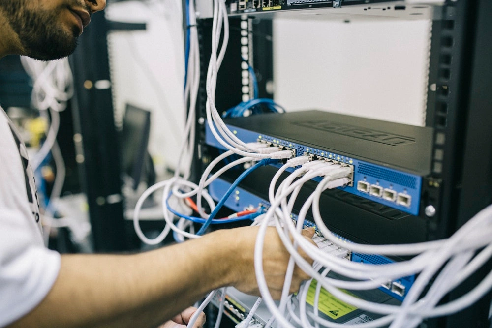 a man connecting cables to a stack of network devices