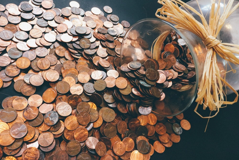 pile of coins spilled on a table from a jar