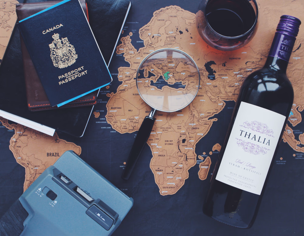a map with a looking glass, glass of wine, an analogue camera and a passport on it