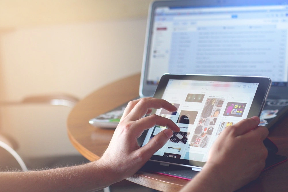 hand holding a tablet with visible clothing articles and accessories