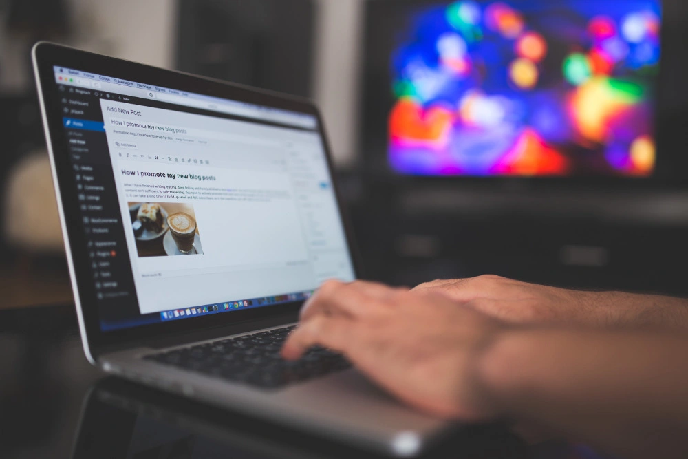 a laptop close to a blurred out high definition TV