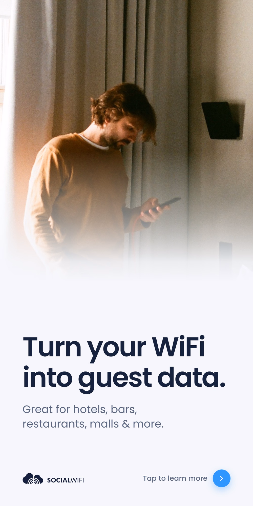 Man checking his phone next to a WiFi access point mounted on the wall, with the headline 'Turn your WiFi into guest data'