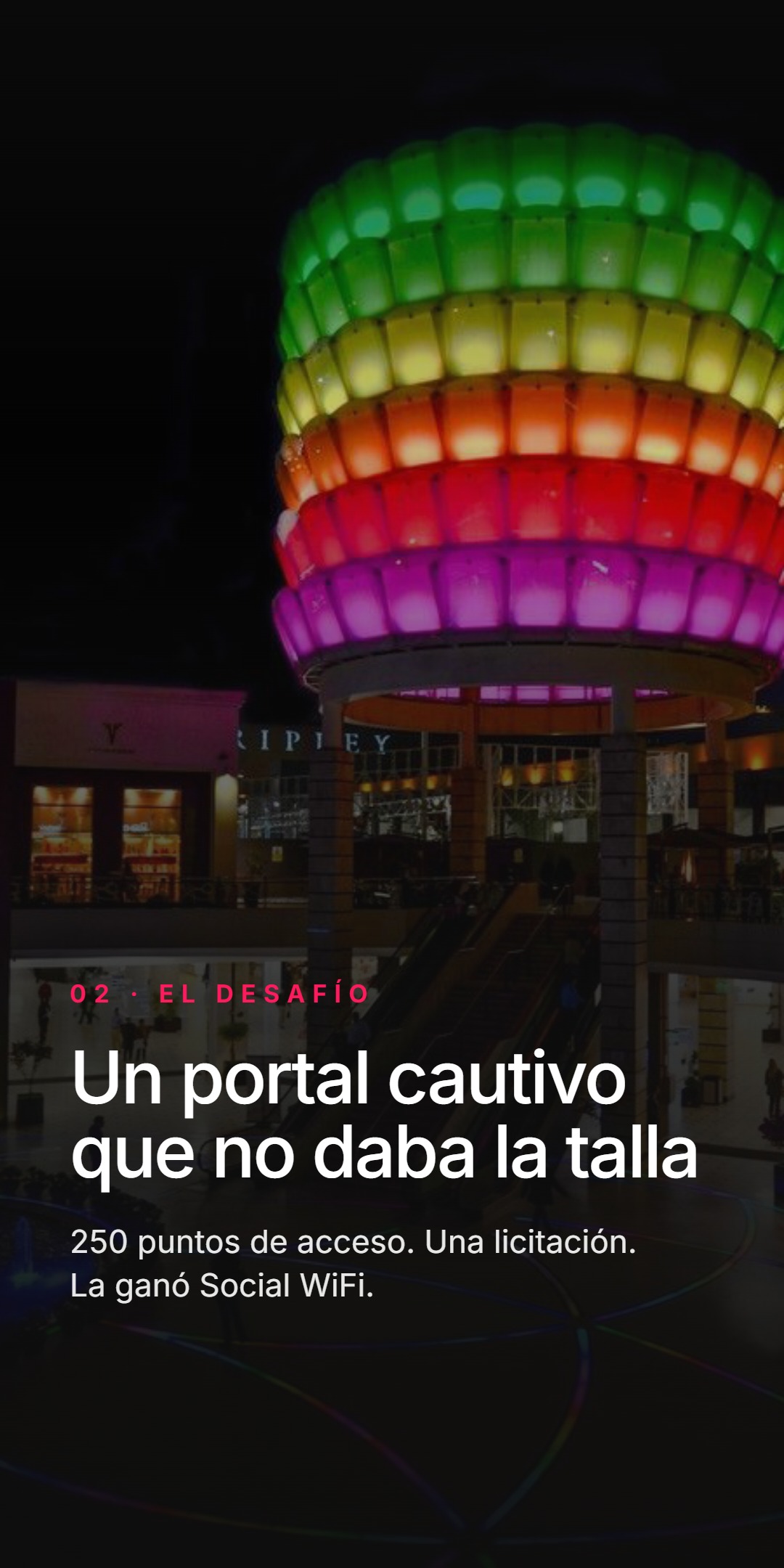 Escultura colorida e iluminada en forma de farol sobre la entrada del centro comercial. Etiqueta 02 - El desafío, titular Un portal cautivo que no daba la talla, datos: 250 puntos de acceso, una licitación, la ganó Social WiFi.