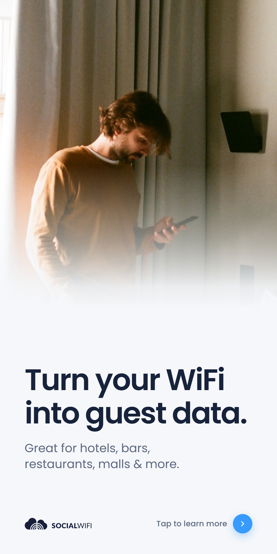 Man checking his phone next to a WiFi access point mounted on the wall, with the headline 'Turn your WiFi into guest data'