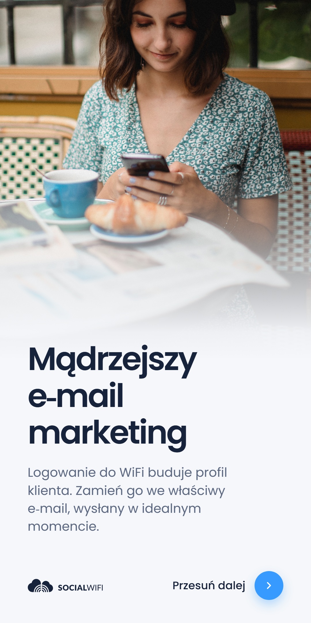 Kobieta relaksująca się przy stoliku w kawiarni z kawą i rogalikiem, sprawdzająca telefon, obok nagłówka 'Mądrzejszy e-mail marketing'